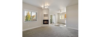 A spacious living room with a fireplace and a carpeted floor.