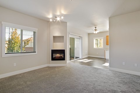 A spacious living room with a fireplace and a carpeted floor.