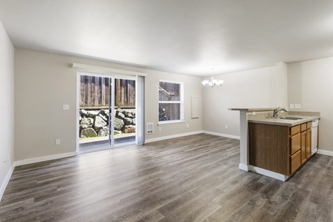 an empty living room with a large window and a kitchen