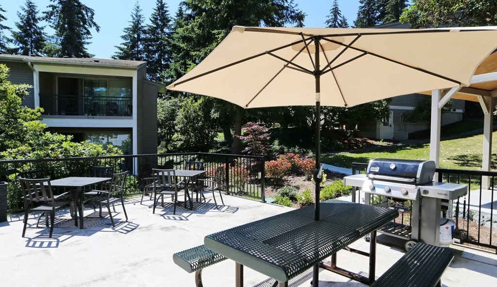 a patio with tables and chairs and an umbrella