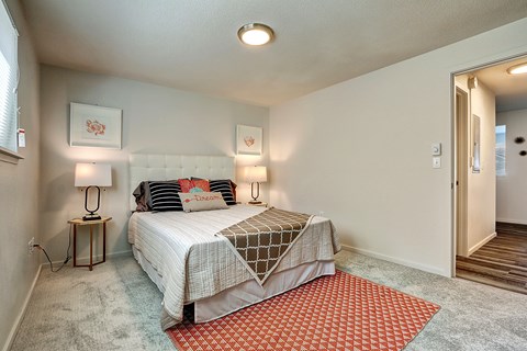 A bedroom with a bed, two lamps, and a rug.