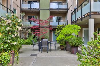 a patio with a table and chairs in front of an apartment building