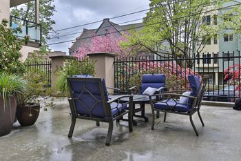 a patio with chairs and a table in front of a fence