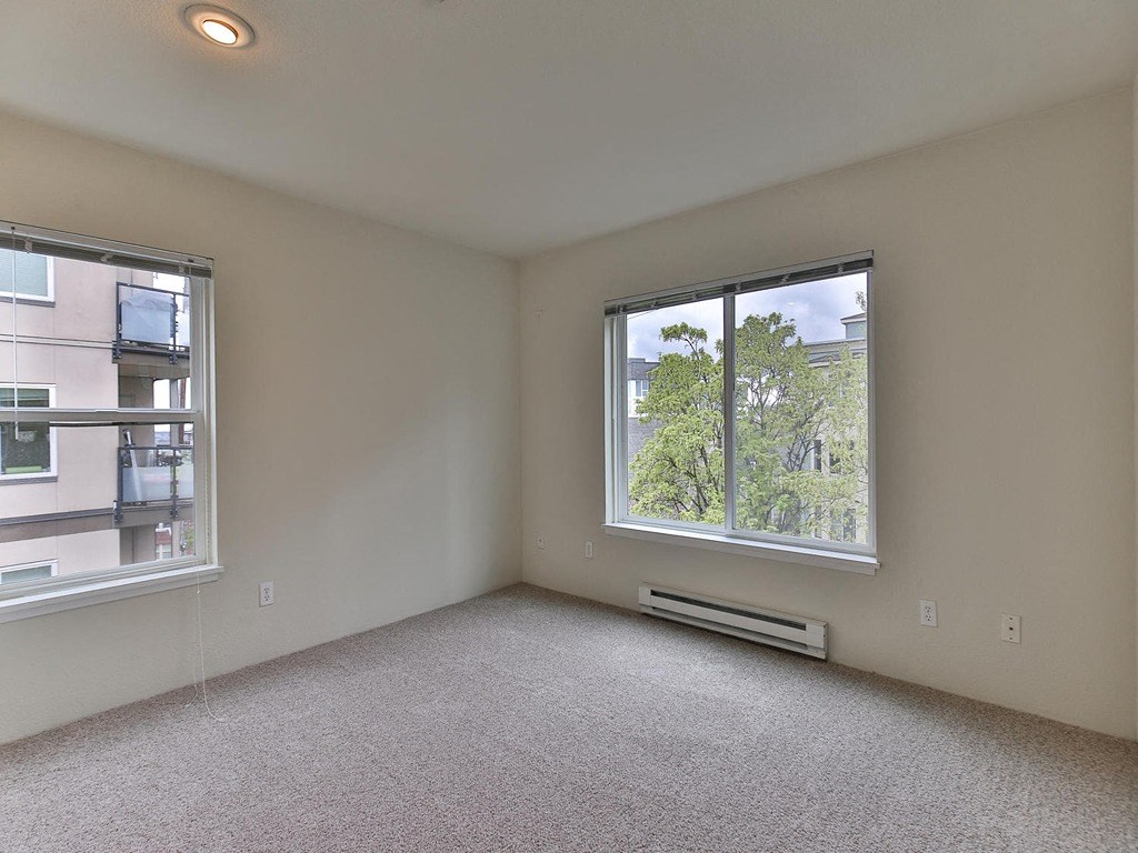 the living room of an empty apartment with two windows