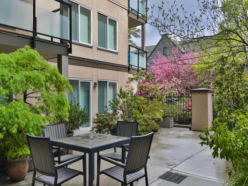 a patio with a table and chairs in front of a building