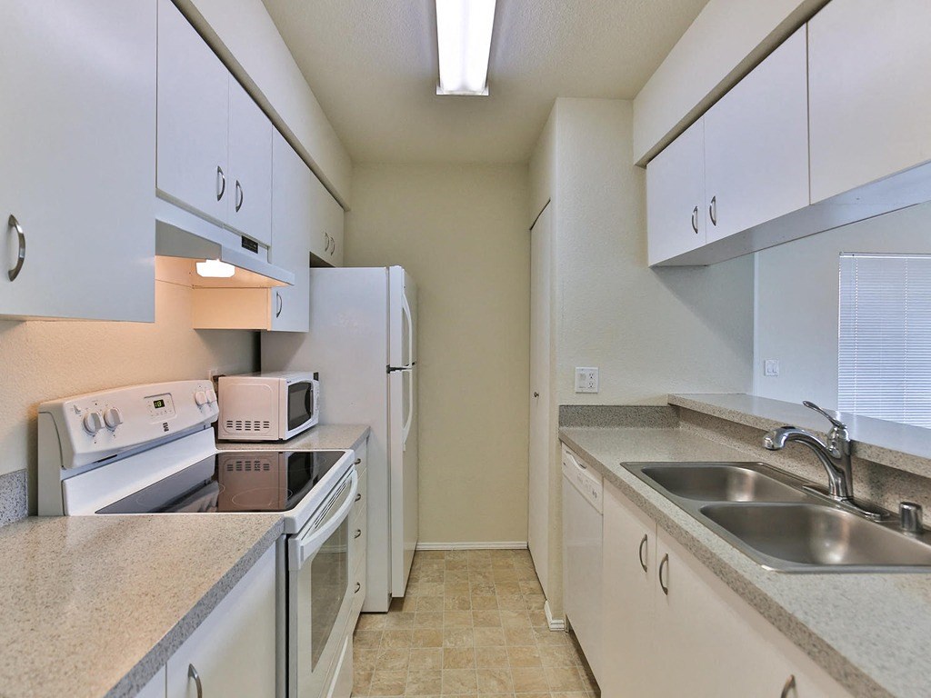a kitchen with white cabinets and appliances and a sink