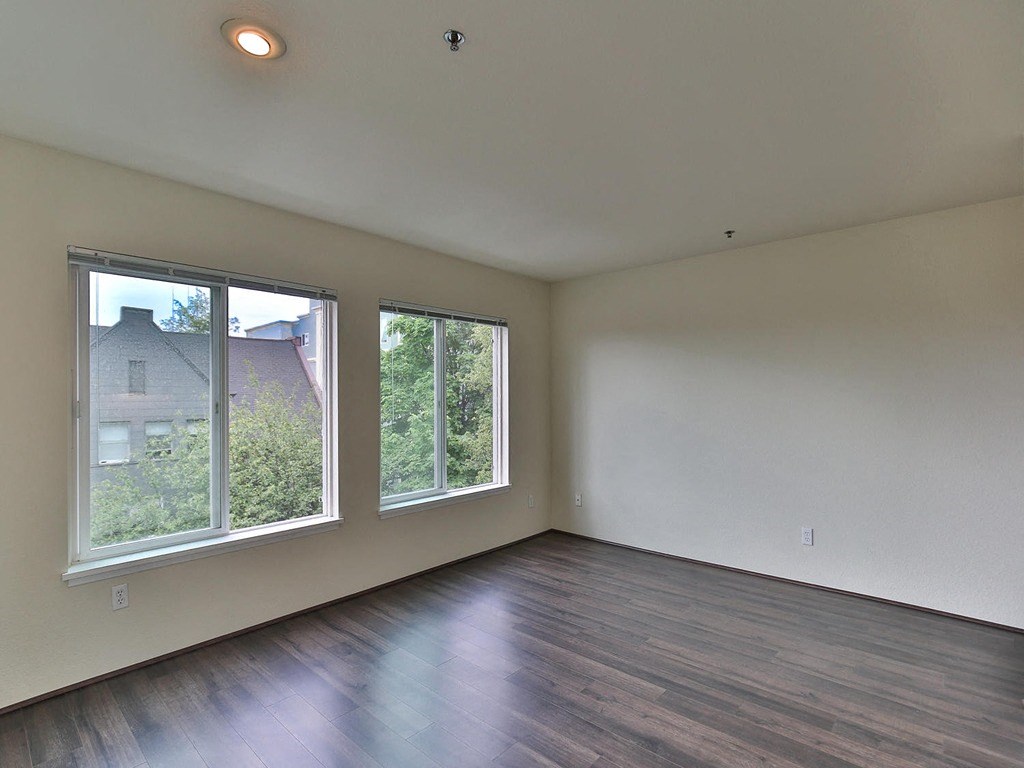 an empty living room with wood floors and large windows