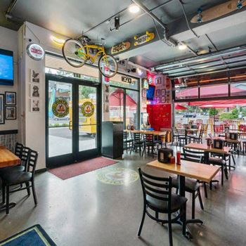 A restaurant with tables and chairs and a bicycle hanging from the ceiling.