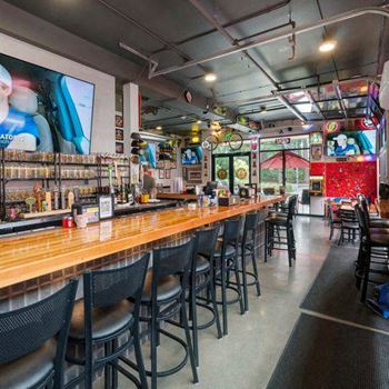 A bar with black chairs and a wooden counter.