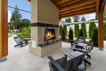 A modern outdoor patio with a fireplace and seating area.