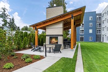 A modern outdoor patio with a fireplace and seating area.