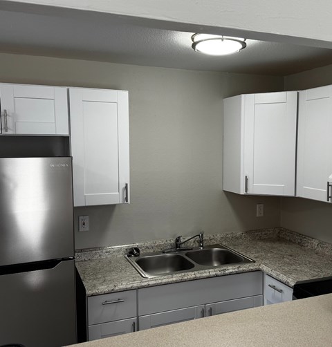 A kitchen with a granite counter top and white cabinets.