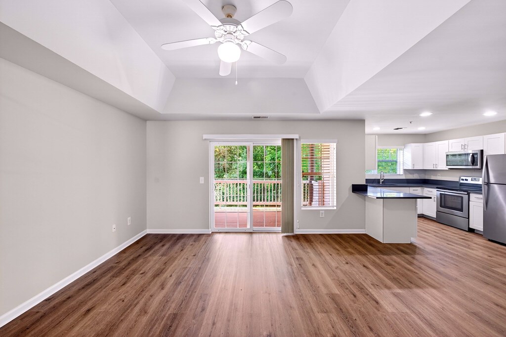 A spacious kitchen with a wooden floor and a ceiling fan.