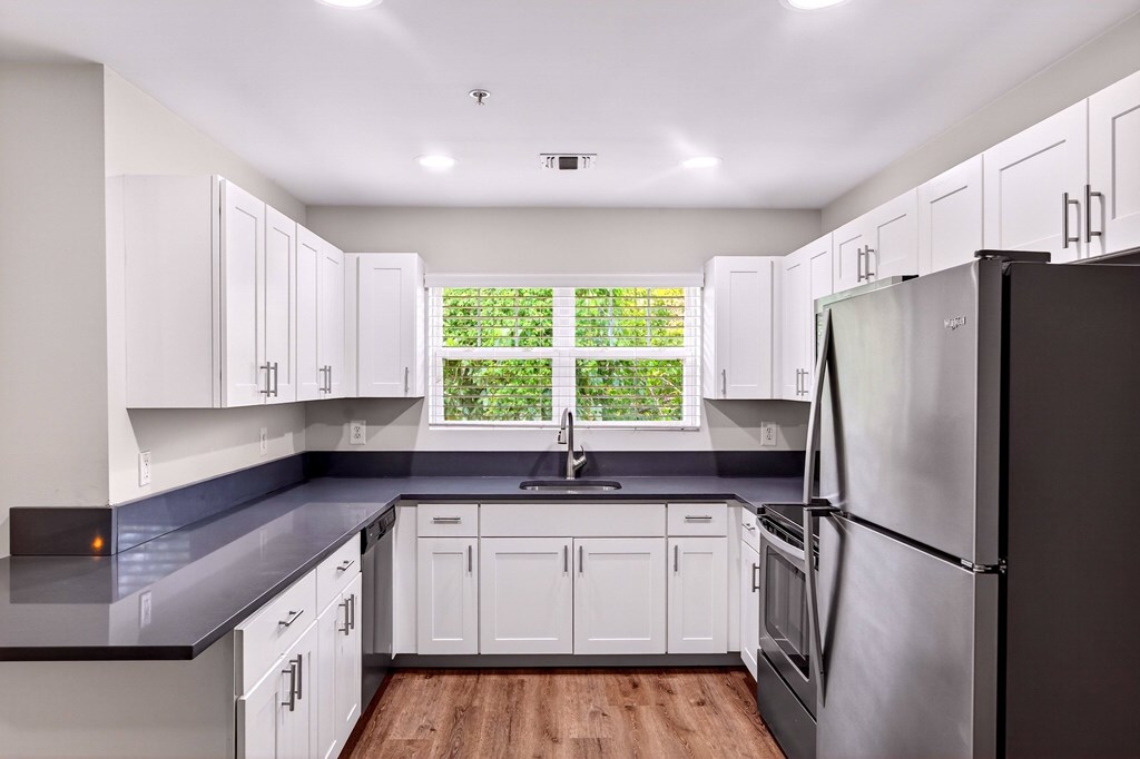 A kitchen with white cabinets and a black countertop.