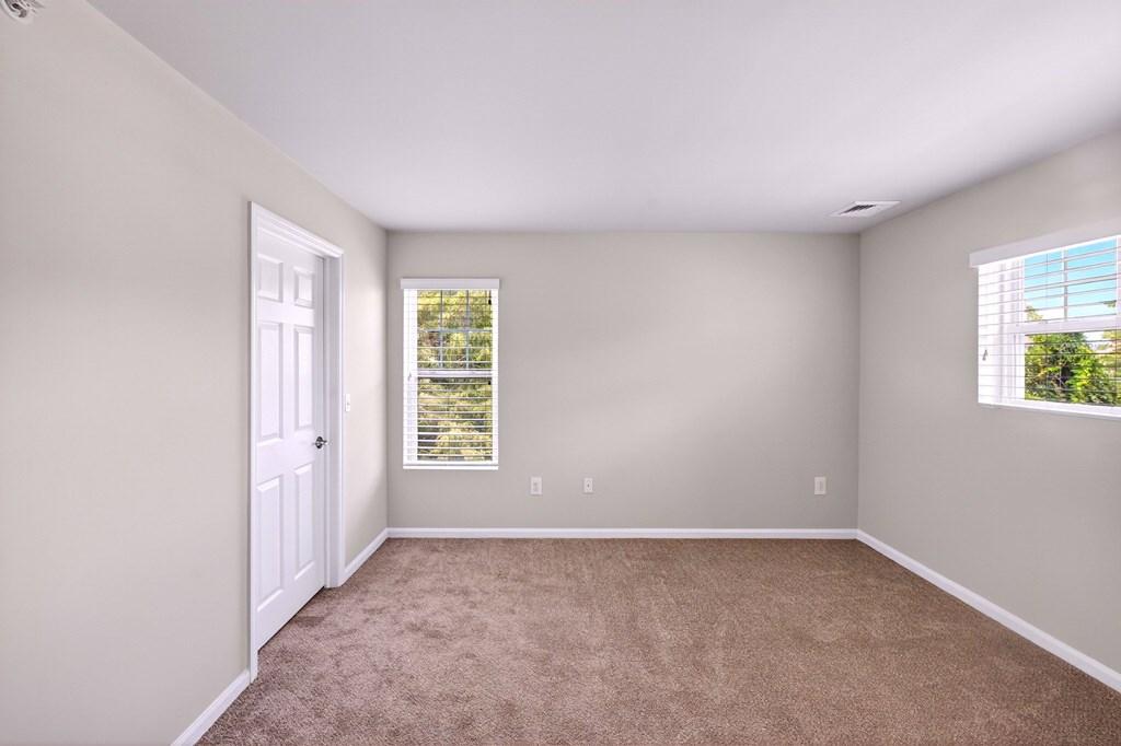 A room with a carpeted floor and a window with blinds.