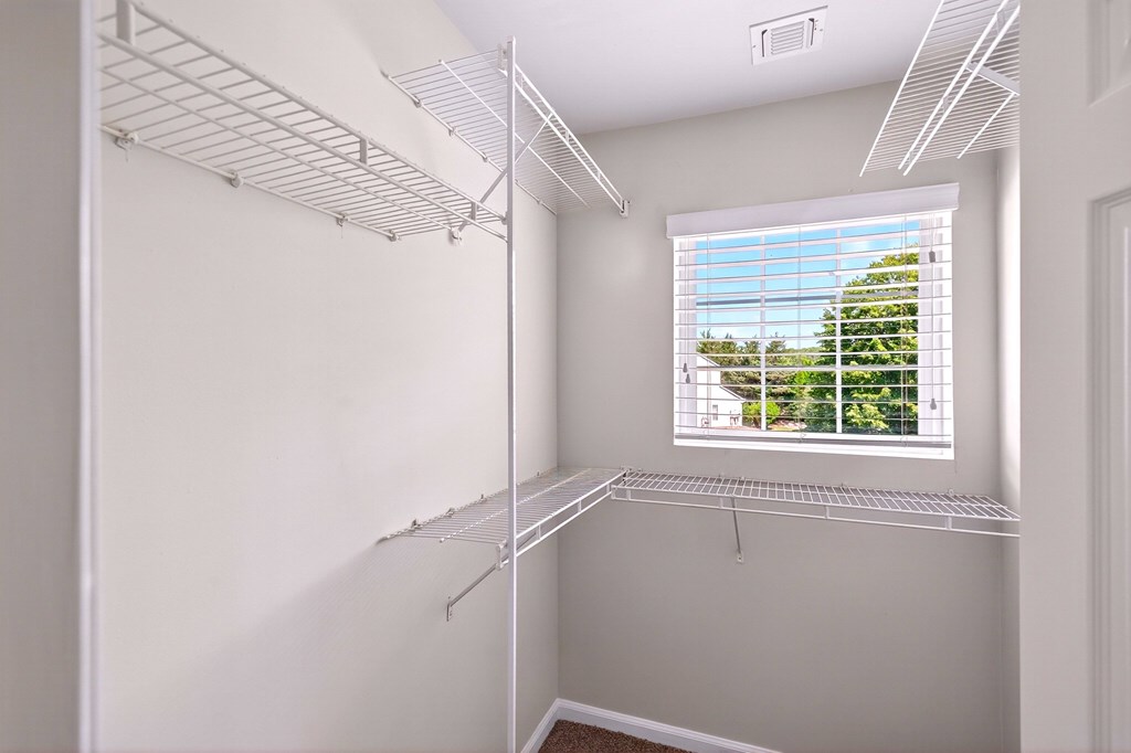 A white room with a window and a wall-mounted shelf.