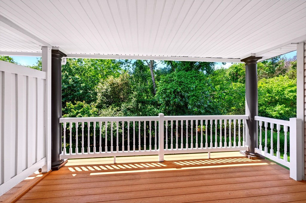 A wooden deck with a white railing and pillars.