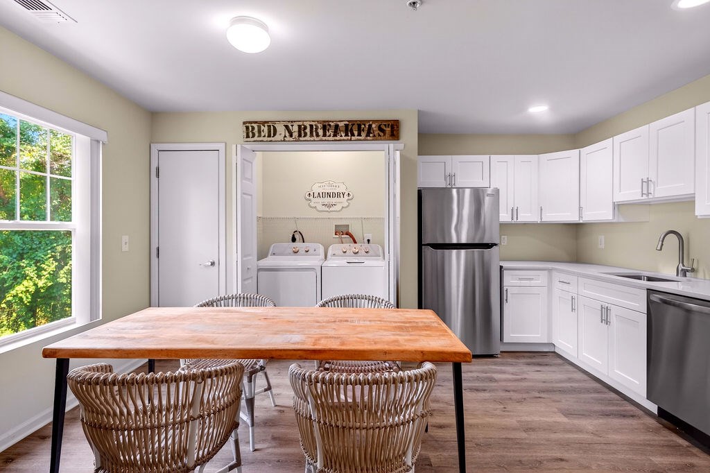 A kitchen with a wooden table and chairs in front of a wall with a sign that says Bed Breakfast.