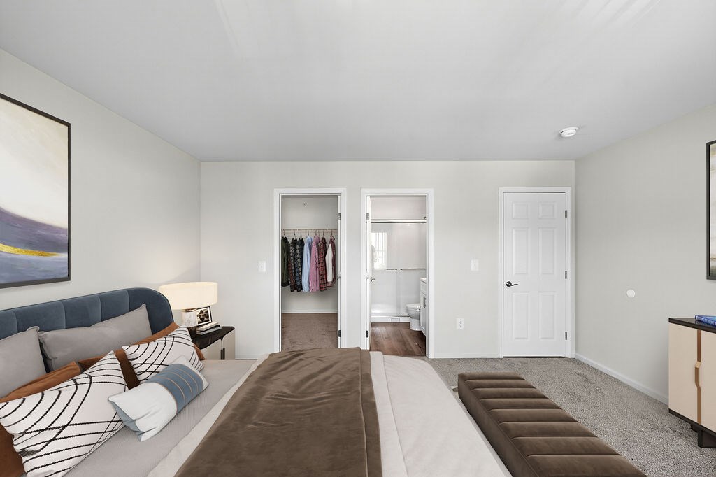 A bedroom with a bed, a couch, and a painting on the wall.