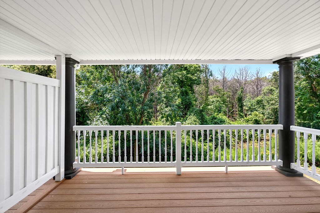 A white porch with a wooden floor and a white railing.