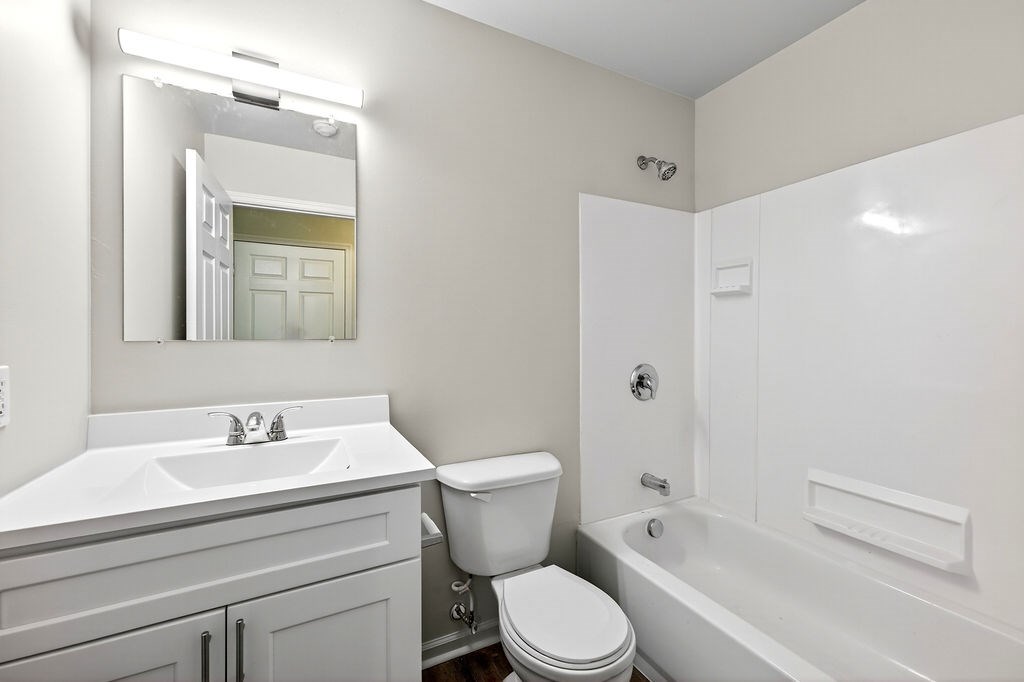 A white bathroom with a toilet, sink, and bathtub.