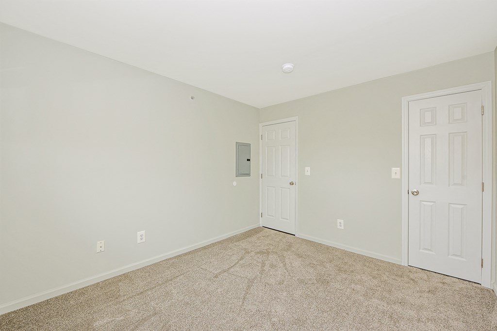 a bedroom with a carpeted floor and a white door  at Platt Gardens, West Babylon, NY