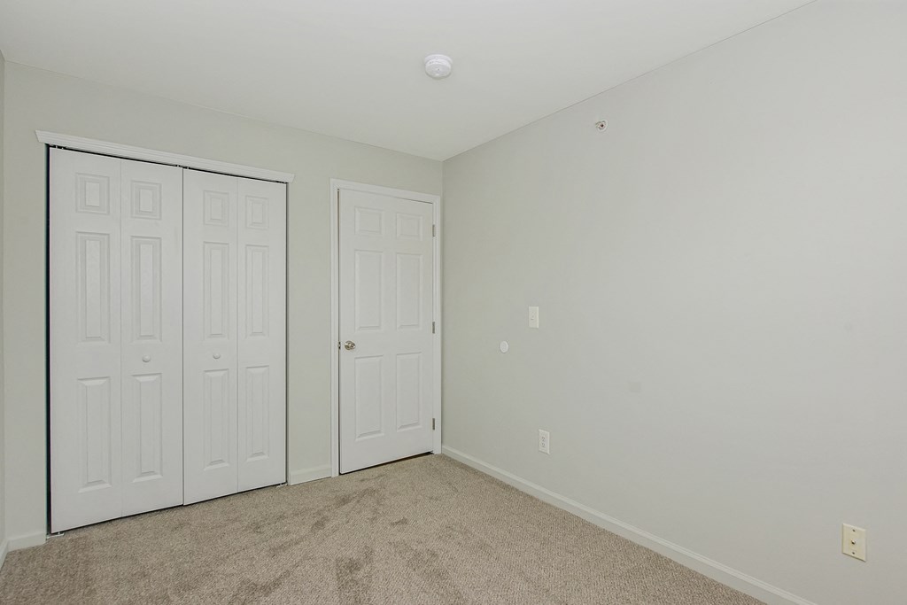 a bedroom with two doors and a carpeted floor  at Platt Gardens, West Babylon, NY, 11704