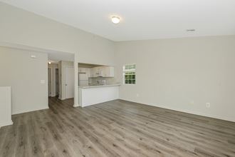 an empty living room with a kitchen in the background  at Platt Gardens, West Babylon, 11704