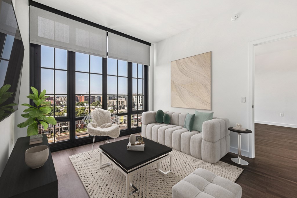 A living room with a large window and a view of the city.