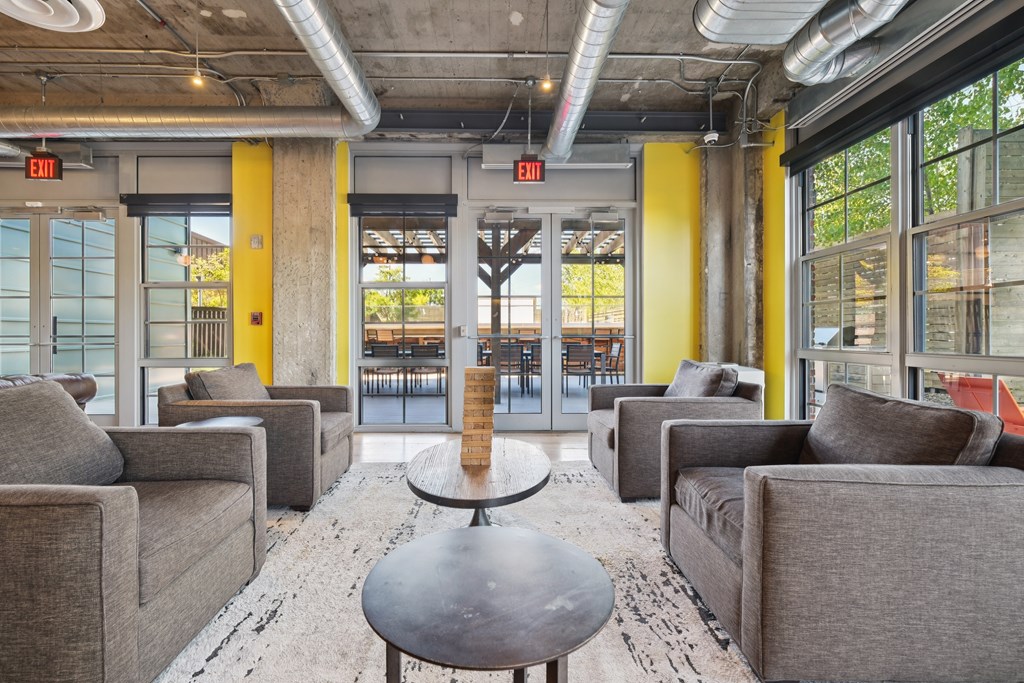 A large room with grey couches and a round table in the middle.