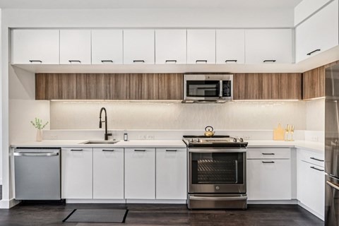 A modern kitchen with white cabinets and a wooden backsplash.