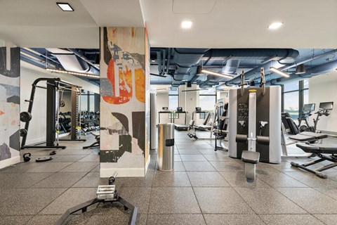 A gym with a variety of equipment including treadmills, weights, and exercise machines.