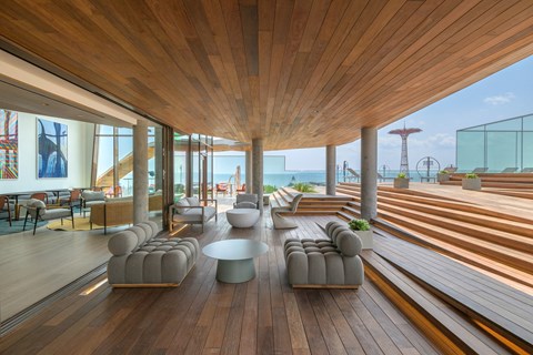 a lounge area with chairs and tables and a view of the beach