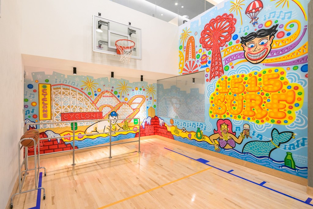 a basketball court with a mural on the wall and a wooden floor