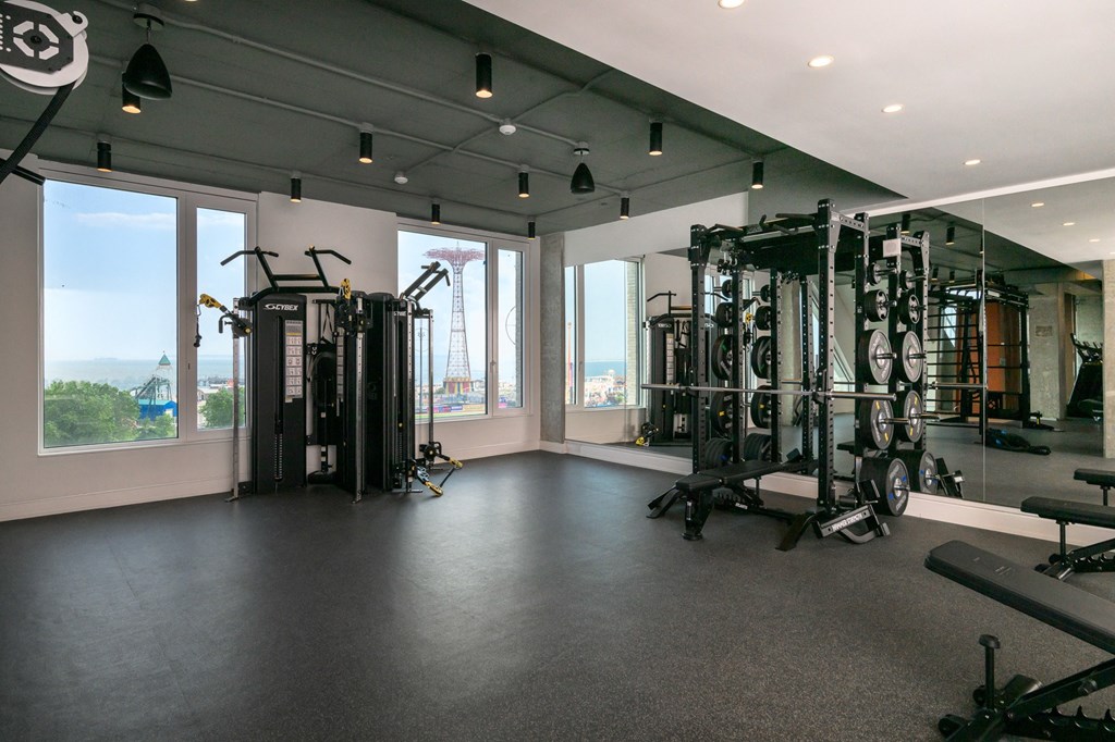 a gym with exercise equipment and windows with a view of the city