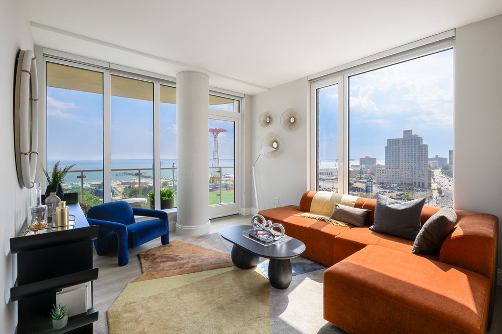 a living room with orange couches and a view of the city and the ocean