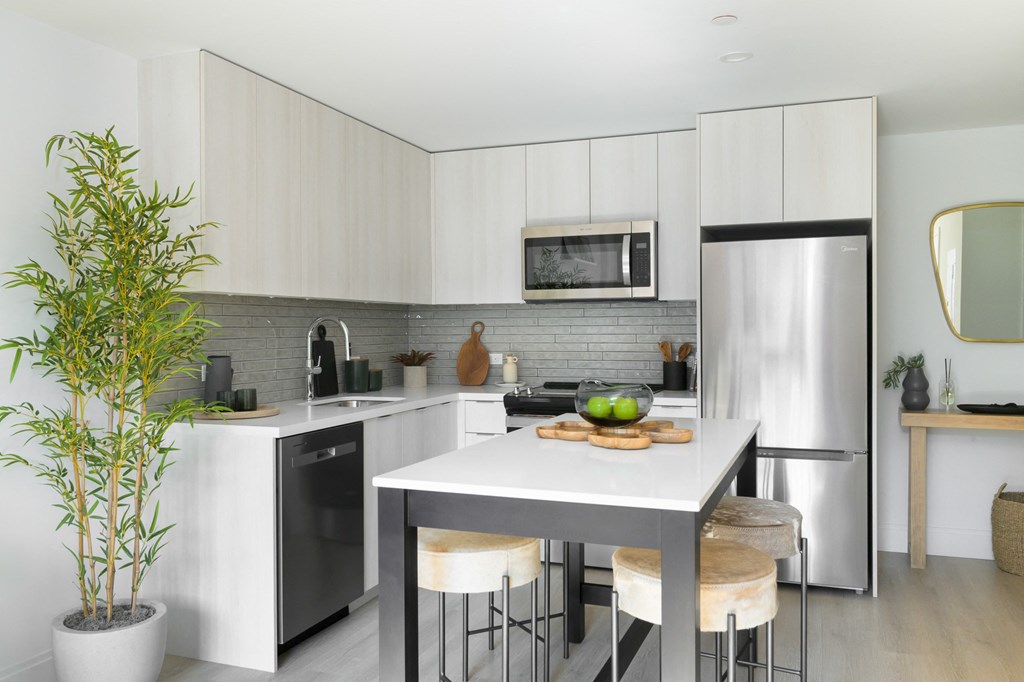 a kitchen with white cabinets and stainless steel appliances and a white table