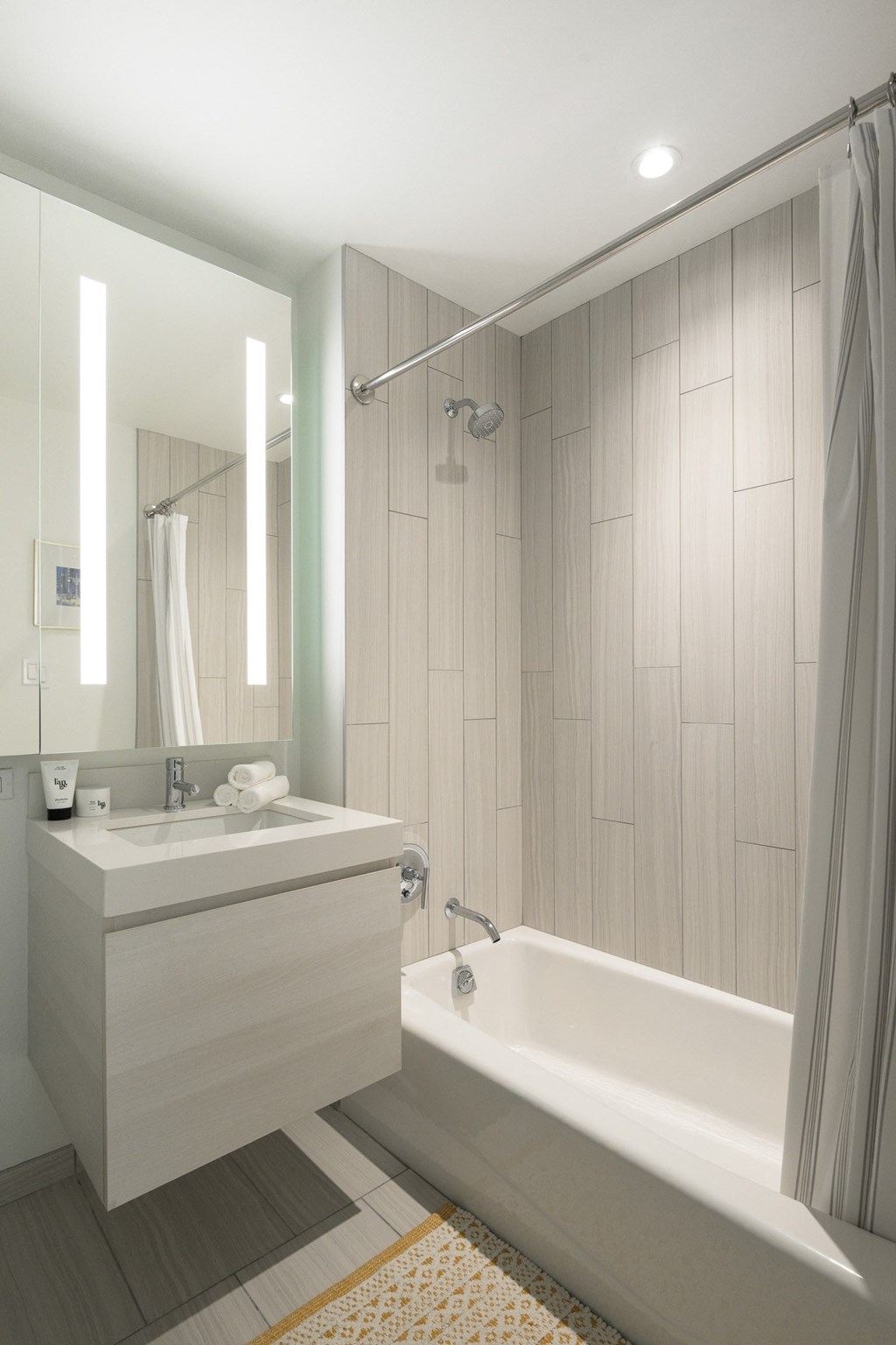 a white bathroom with a tub and a sink and a mirror