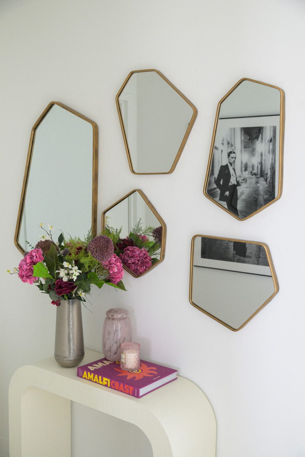 a wall of mirrors and a vase with flowers on a table