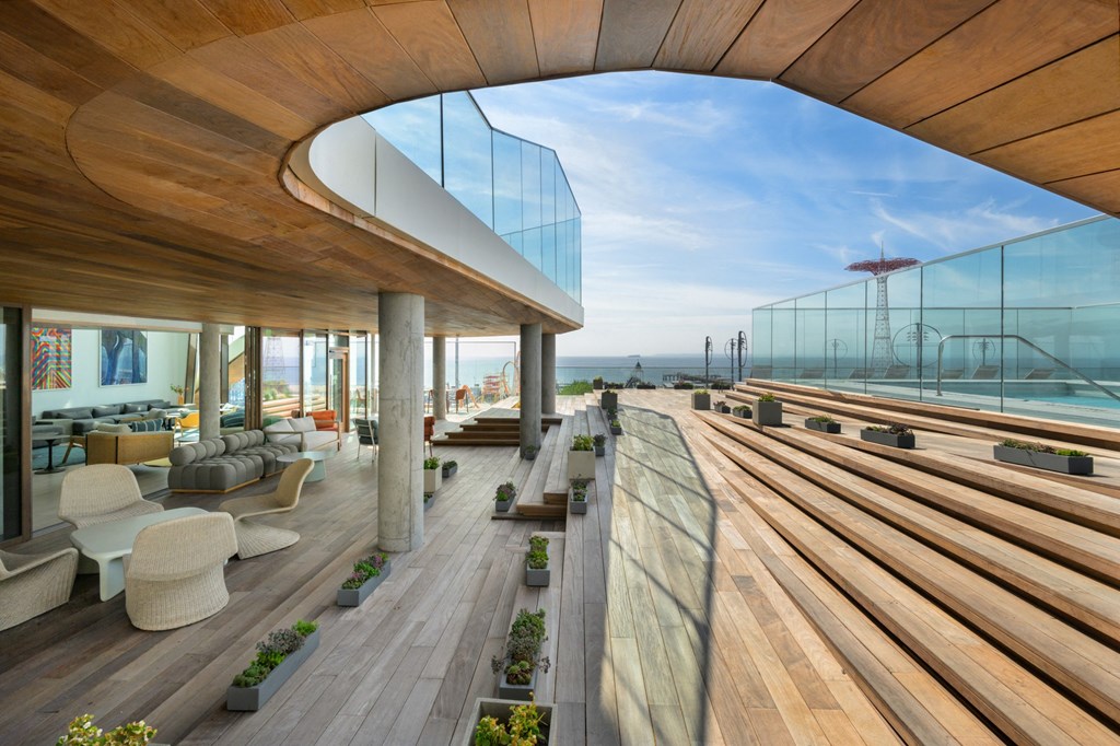 a lounge area with wooden floors and a balcony overlooking the ocean