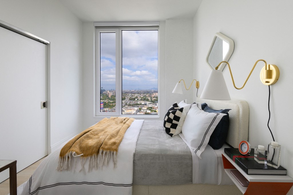 a bedroom with a bed and a window with a city view