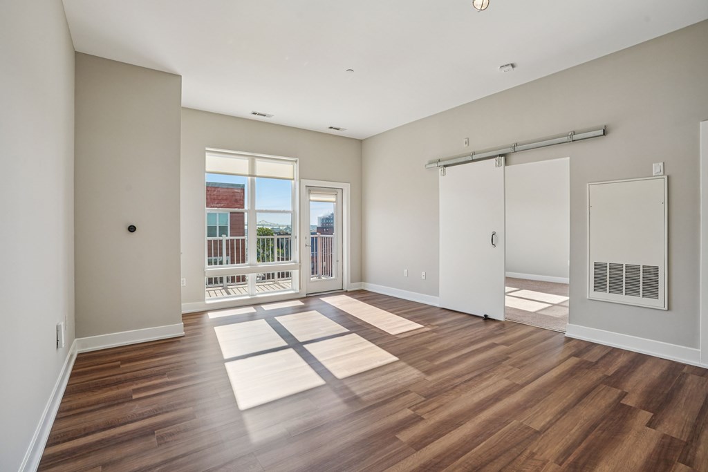 A room with wooden floors and a sliding glass door leading to a balcony.
