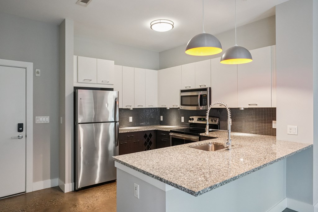 A kitchen with a granite countertop and stainless steel appliances.