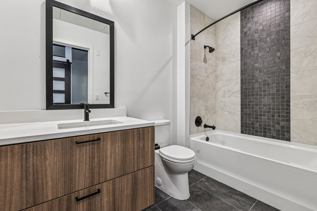 A white sink with a mirror above it and a white toilet next to a bathtub.