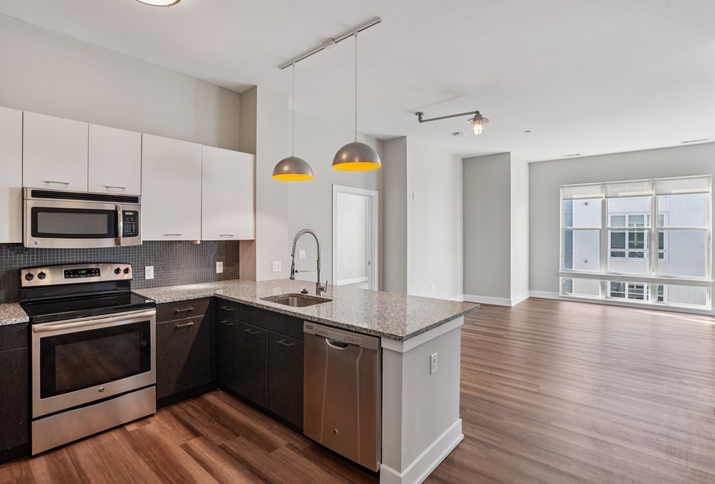 A modern kitchen with dark wood floors and stainless steel appliances.
