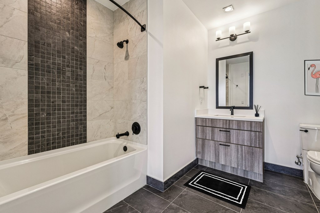 A bathroom with a white tub and a wooden vanity.
