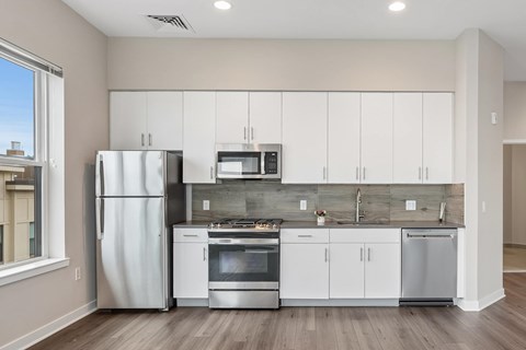 A modern kitchen with white cabinets and stainless steel appliances.