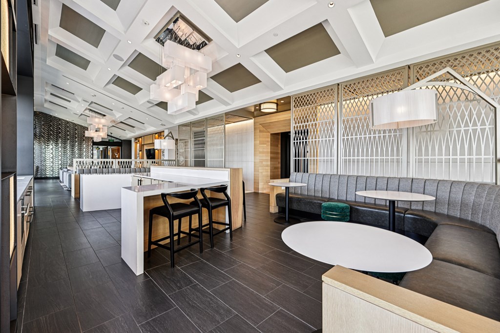 A modern dining area with a white counter and black chairs.