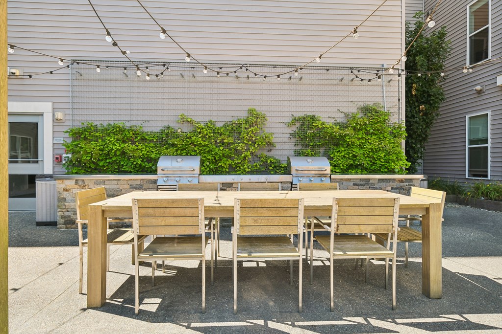 A wooden table with four chairs is set up on a patio.