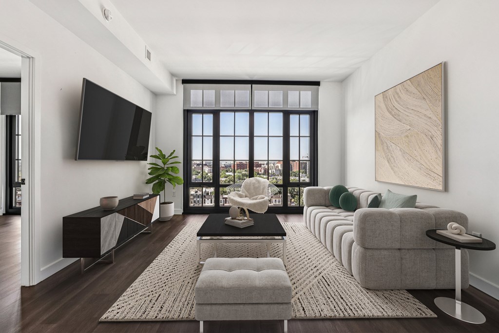 A living room with a large window, a flat screen TV, and a long couch.